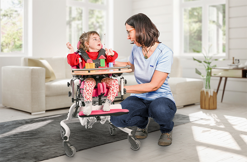 Mitarbeiterin beim Ausmessen von einem Therapiestuhl mit einem Kind